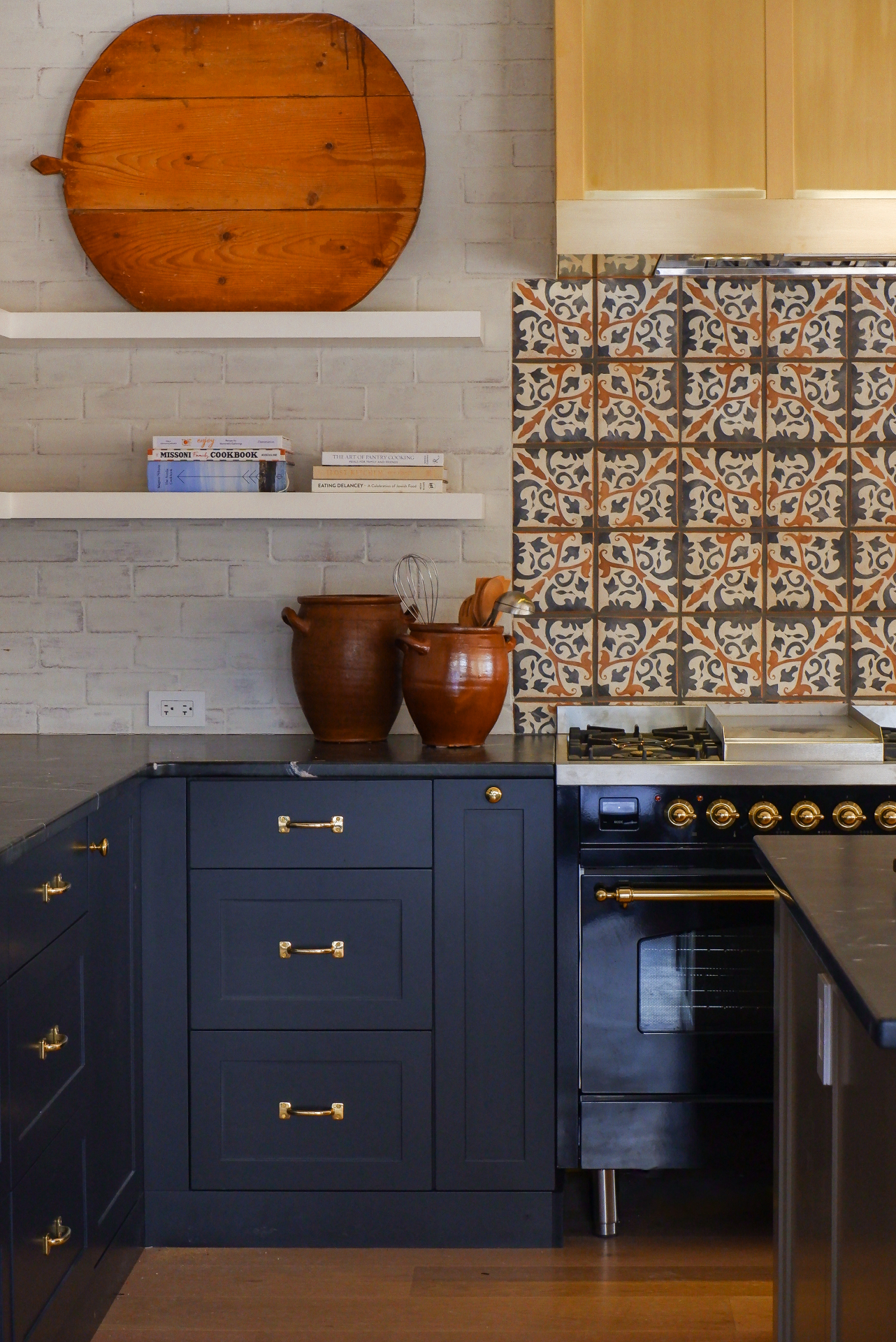Navy shaker cabinetry with brass cup pulls and patterned tile backsplash