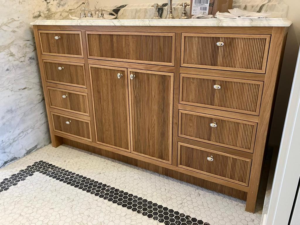 Reeded white oak bathroom vanity with marble top and porcelain knobs