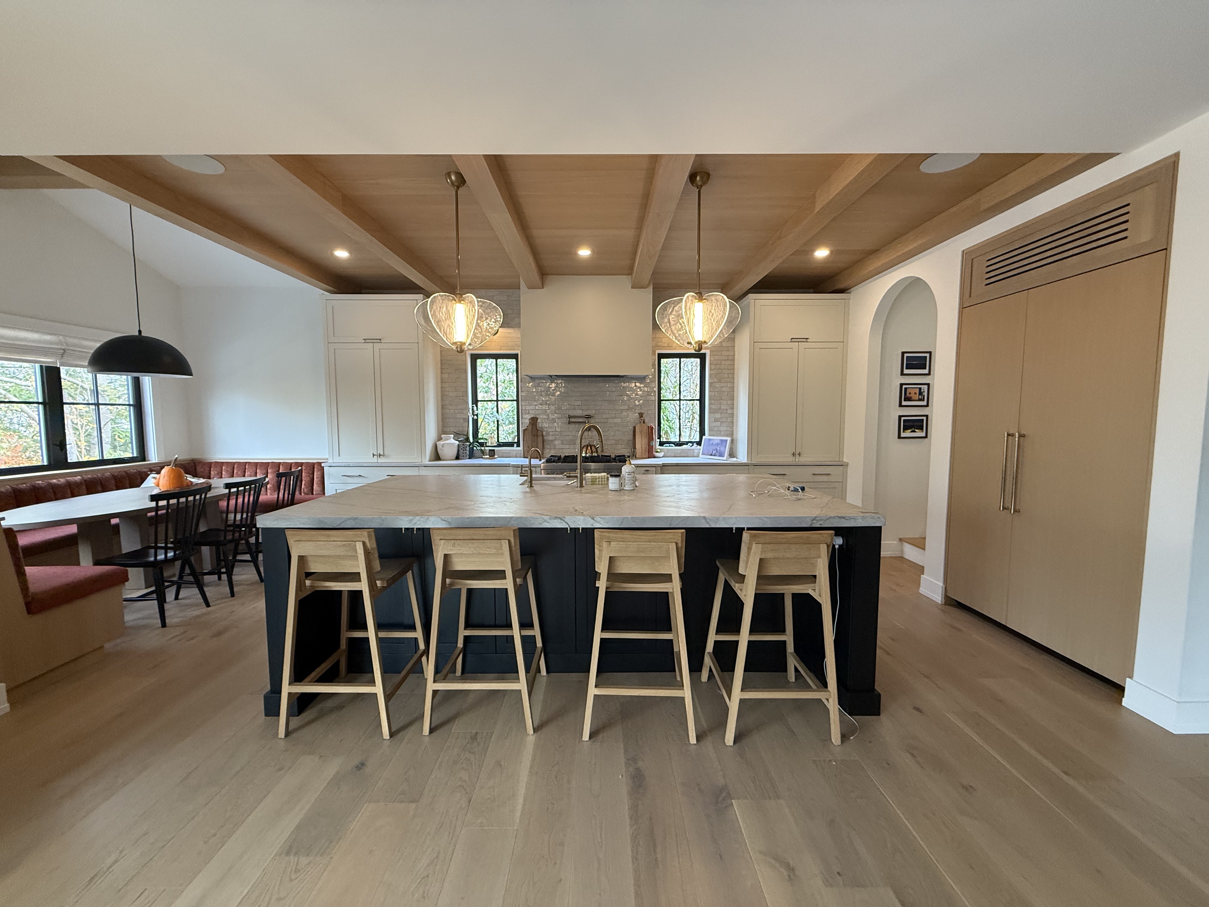 Transitional kitchen with a navy island, white oak beamed ceiling, and marble worktop