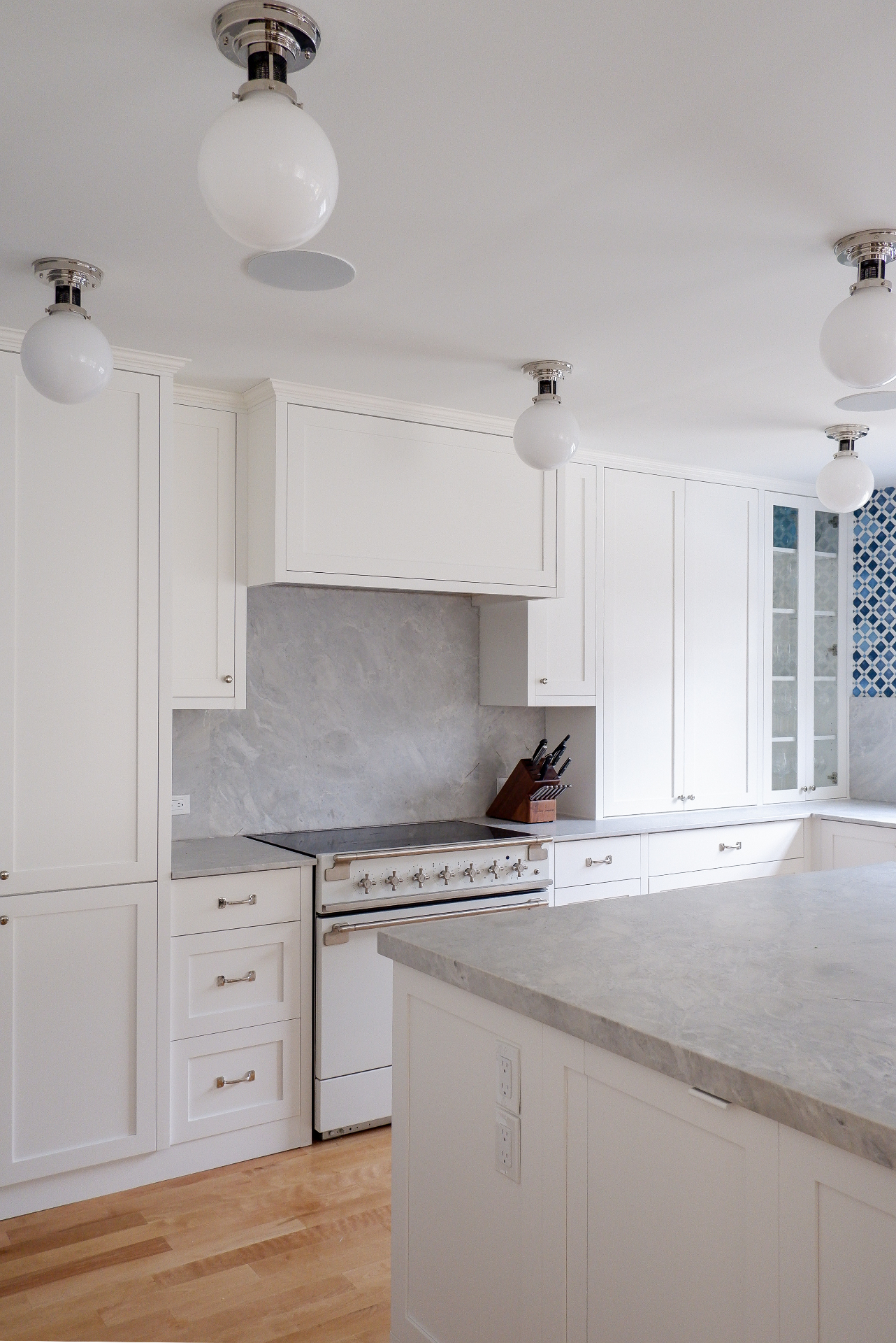Custom white kitchen with marble backsplash and glass-front upper cabinets
